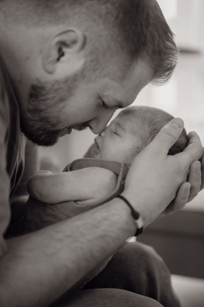 Babyfoto eines Papas der sein Kind auf die Stirn küsst