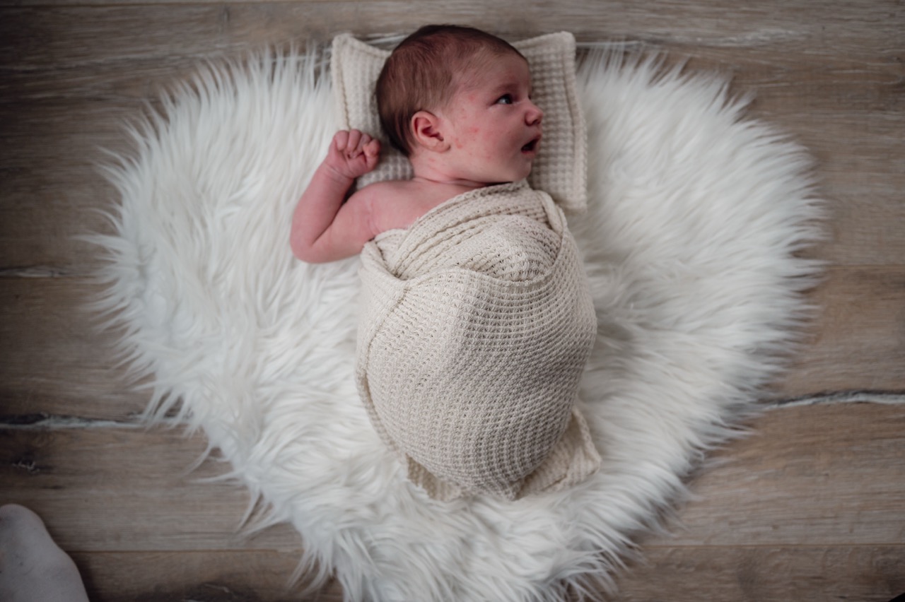 Babyfoto Das Kind Liegt auf eine Fell und ist eingepuckt
