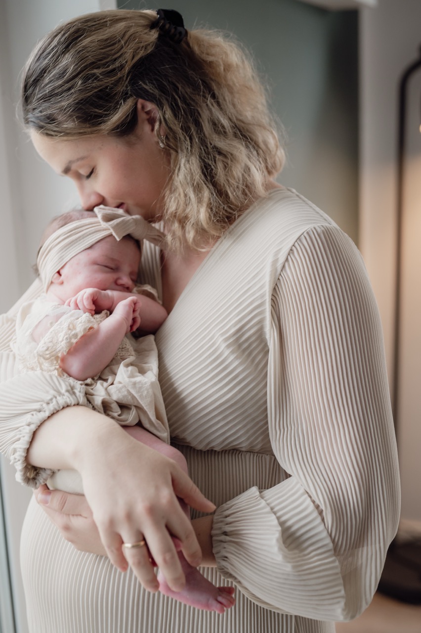 Babyfoto die Mutter küsst ihr Baby auf die Stirn