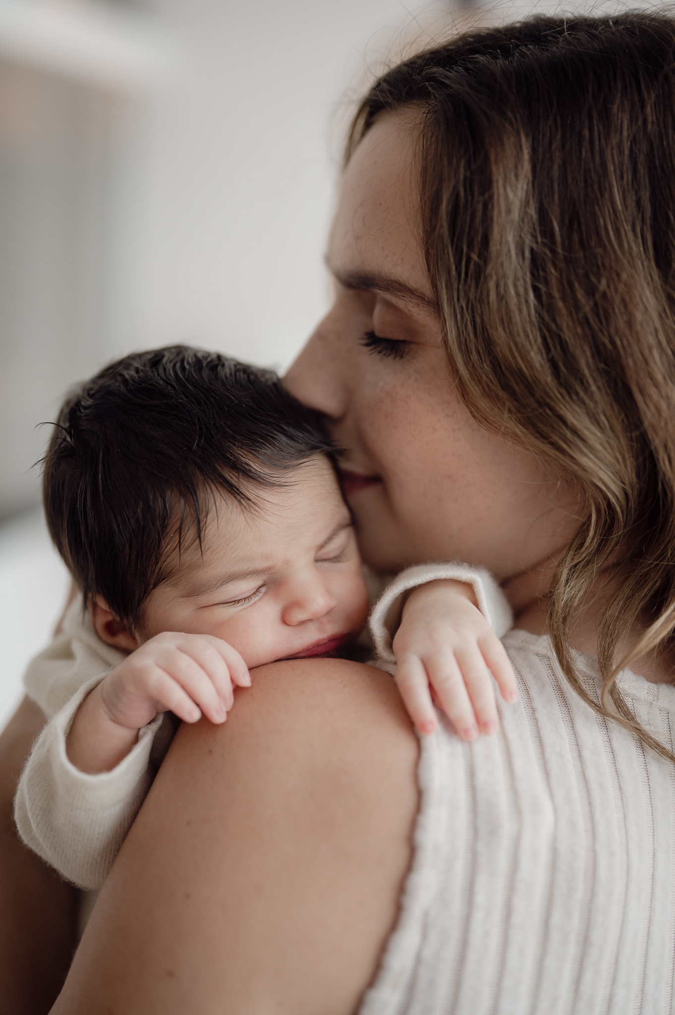Ein Babyfoto wo die Mutter das Baby auf dem Arm hat und küsst
