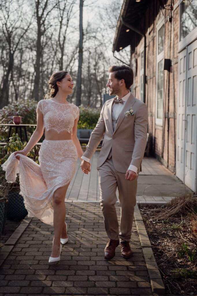 Das Brautpaar geht gemeinsam auf den Hochzeitsfotograf Göttingen zu und lacht sich dabei an auf der Terrasse vom Peak Hotel