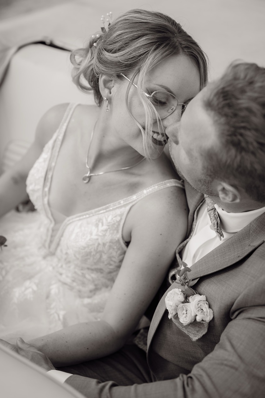 Brautpaar sitzt im Auto und es küsst sich liebevoll Schwarz weiss 