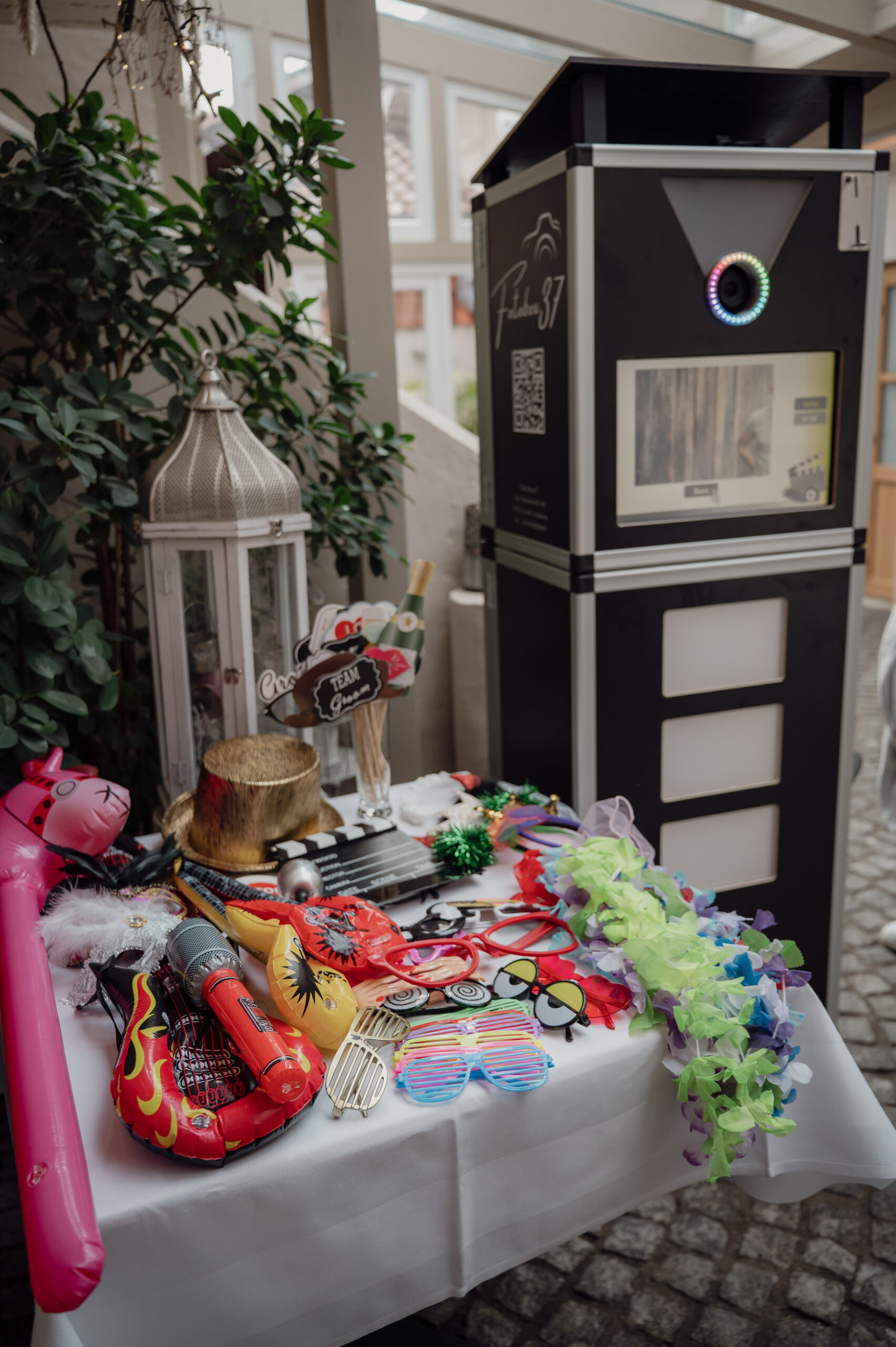 Fotobox steht im Eingang einer Terrasse und auf eine Tisch liegen Requisiten