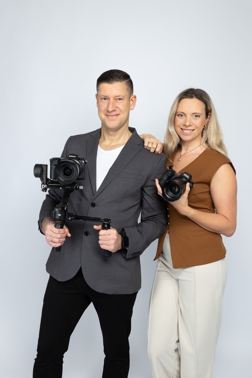 Videograf und Fotografin stehen vor der Kamera mit ihren eigenen Kameras
