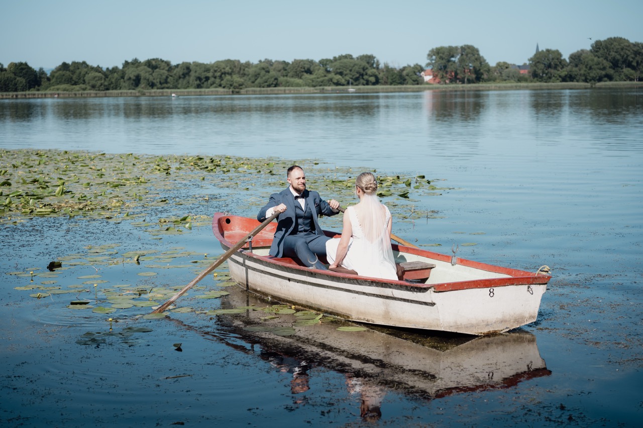 Hochzeitsfvideo Österreich romantisches Brautpaar in einem Ruderboot auf einem idyllischen See, natürliche Outdoor-Hochzeitsfotografie mit Landschaftsromantik in Kassel.